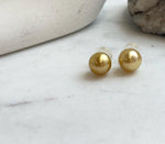Large natural ocean pearl stud earrings in warm tea gold tone.