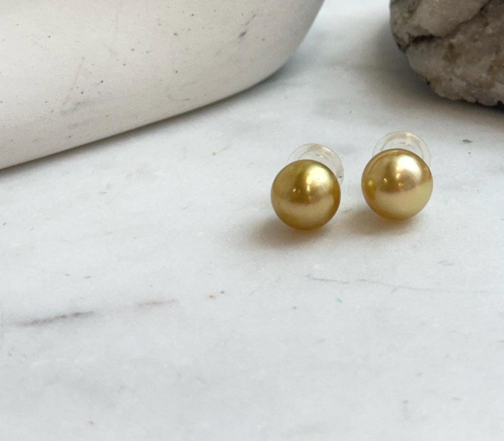 Large natural ocean pearl stud earrings in warm tea gold tone.