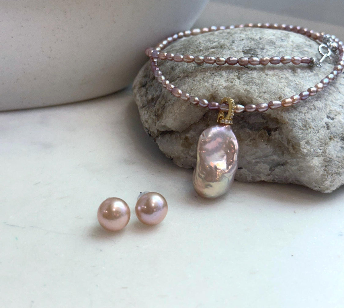 Soft pink rose freshwater pearl necklace displayed with matching pearl earrings.