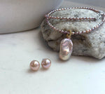 Soft pink rose freshwater pearl necklace displayed with matching pearl earrings.