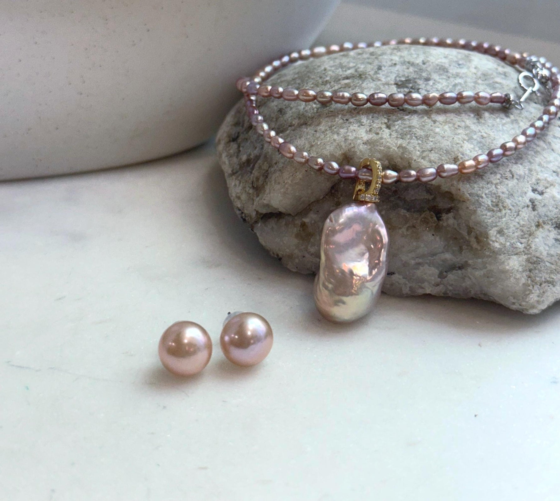 Soft pink rose freshwater pearl necklace displayed with matching pearl earrings.