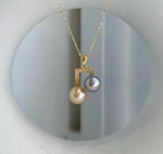 Elegant dual pearl pendant featuring golden and dark Tahitian pearls.