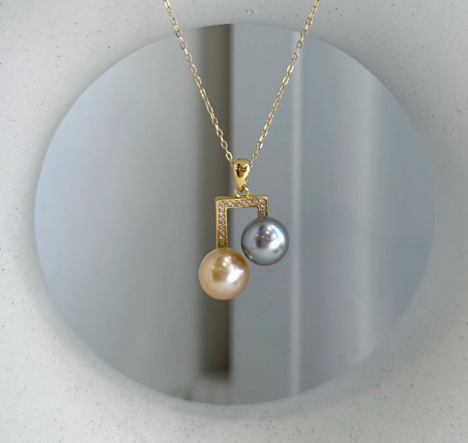 Elegant dual pearl pendant featuring golden and dark Tahitian pearls.