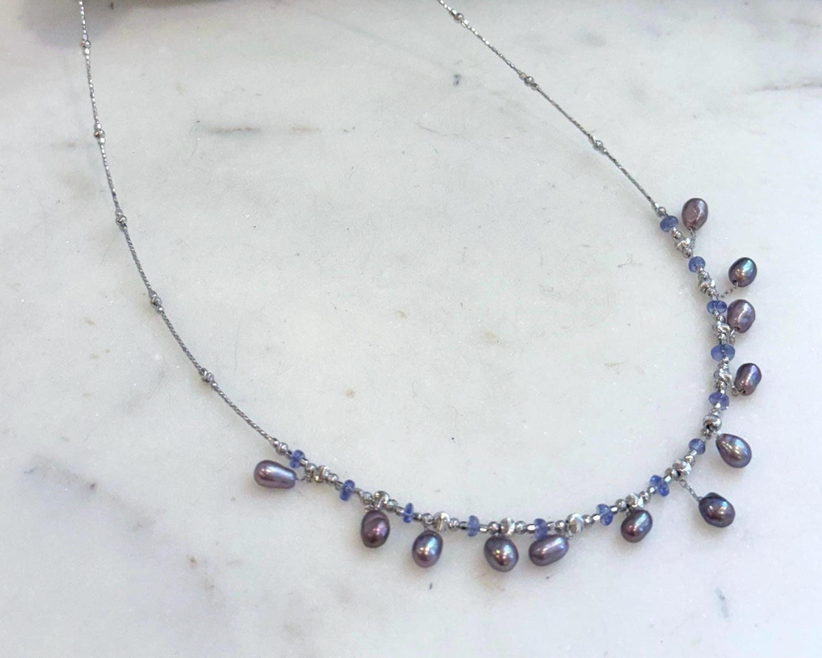 Genuine freshwater Keshi pearl necklace featuring natural Tanzanite accents and mirror luster.