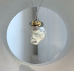 Mirror luster baroque pearl pendant displayed with genuine freshwater pearl earrings on a neutral stone background.