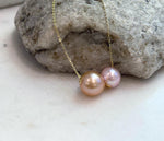 Elegant floating pearl necklace featuring two genuine Edison pearls in warm gold tones.