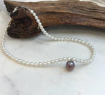 Elegant white pearl necklace featuring a large 12.9mm purple Edison pearl.