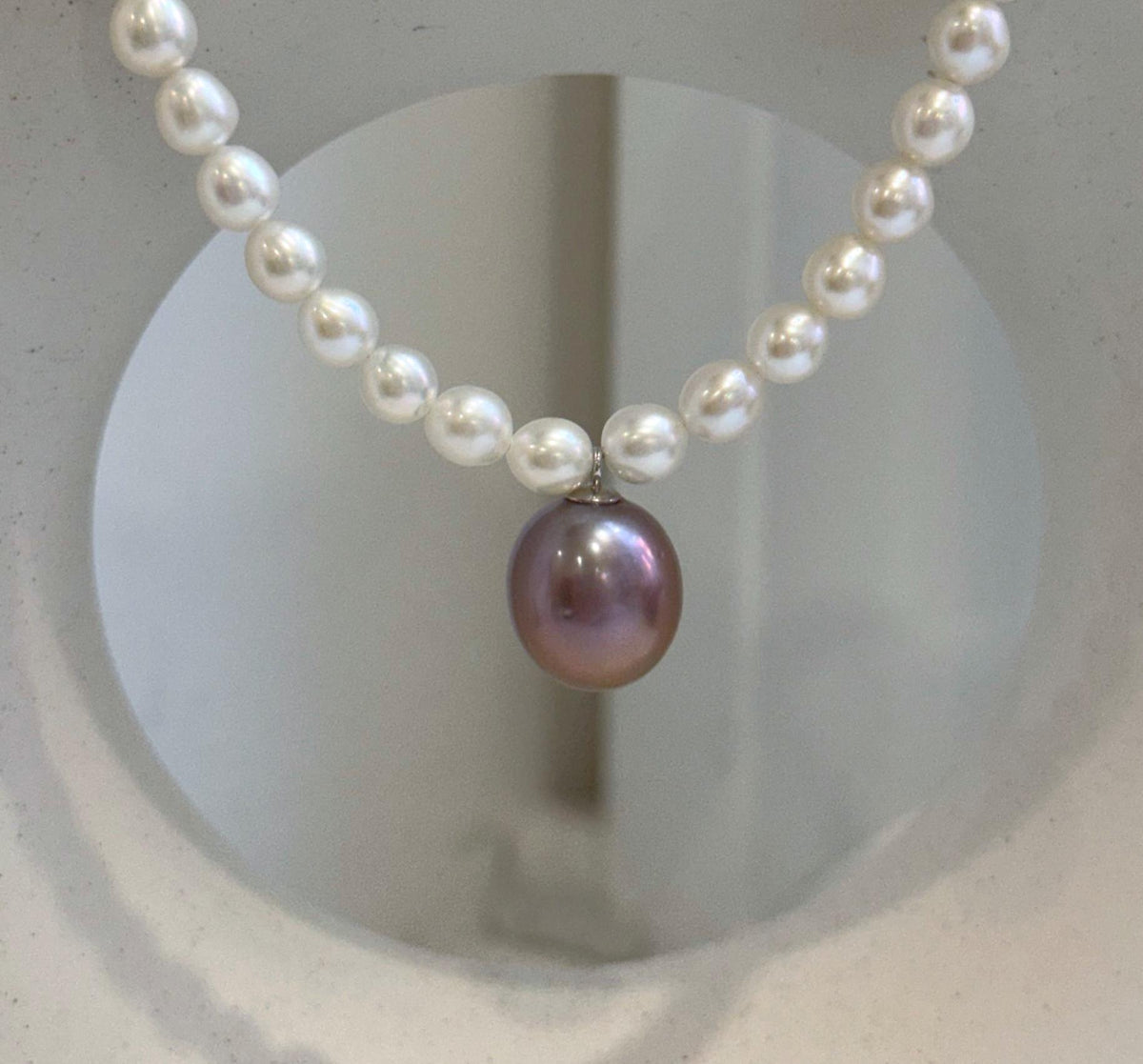 Large purple Edison pearl pendant surrounded by luminous white freshwater pearls.