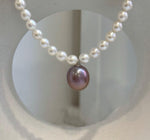 Large purple Edison pearl pendant surrounded by luminous white freshwater pearls.