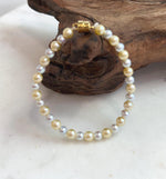 Dainty 4.3–5.5mm pearl bracelet with warm golden and silvery tones.