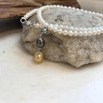 Multicolor triple pearl drop pendant displayed on a classic white freshwater pearl necklace.