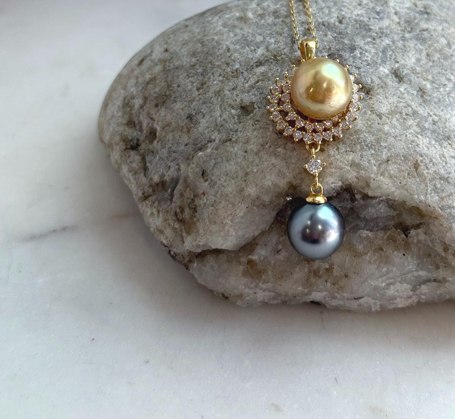 Two premium saltwater pearls in golden and dark Tahitian tones on a minimalist S925 silver setting.