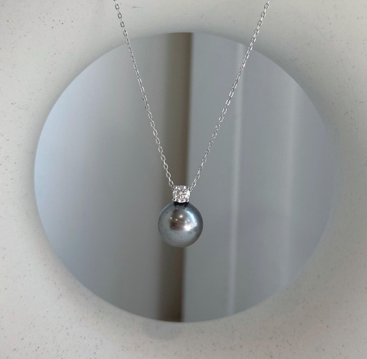 Elly’s 10.9mm Tahitian platinum ocean pearl moissanite pendant with mirror luster.