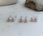 Elegant 9.5mm Edison pearl studs with soft pale pink tones and brilliant mirror luster.