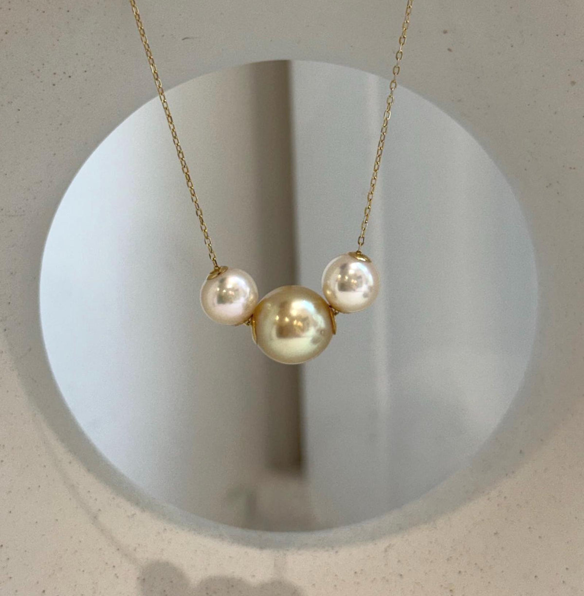 Three-pearl floating pendant with luminous golden South Sea and Akoya ocean pearls.