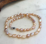 Natural-style freshwater pearl strand showcasing colorful peach, rose and golden Keshi pearls.