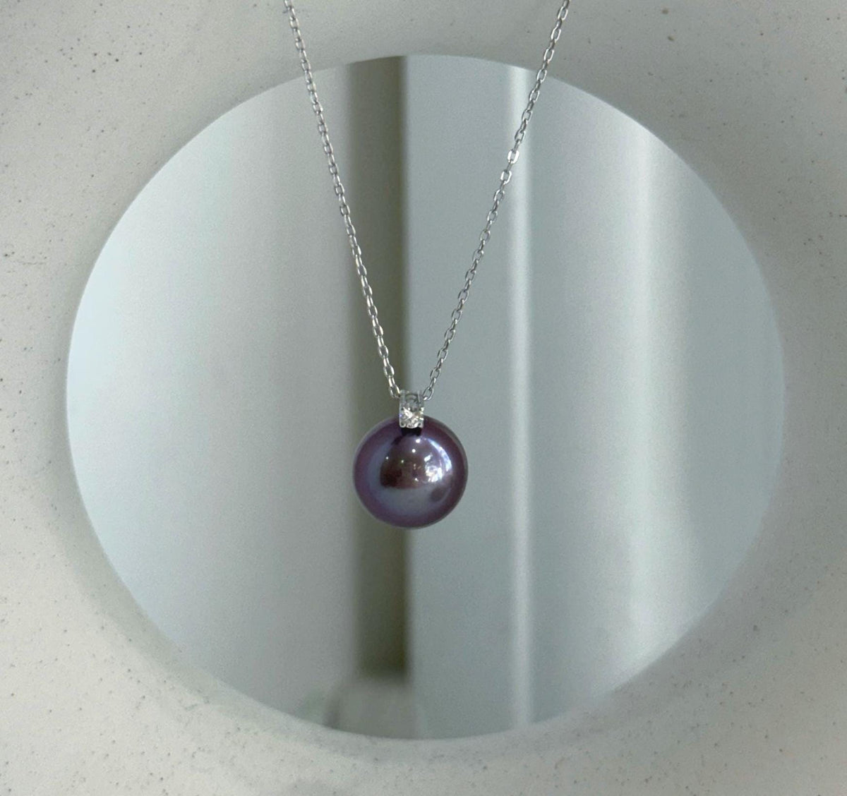 Close-up of 11mm Edison purple pearl with extreme mirror luster, accented by a sparkling natural diamond.