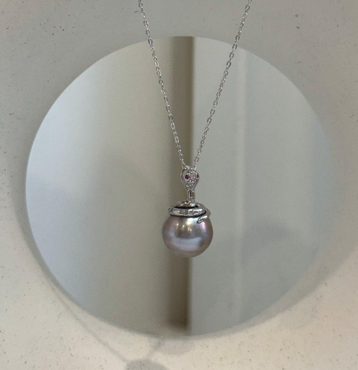 Tahitian platinum pearl snake pendant with a round 11.8mm ocean pearl and brilliant reflective luster.