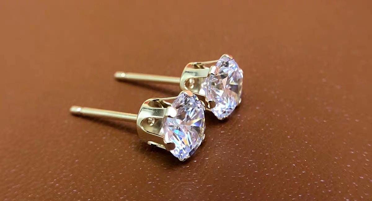 Dainty Au750 18K gold stud earrings with brilliant clear round moissanite stones in secure 6-prong settings.