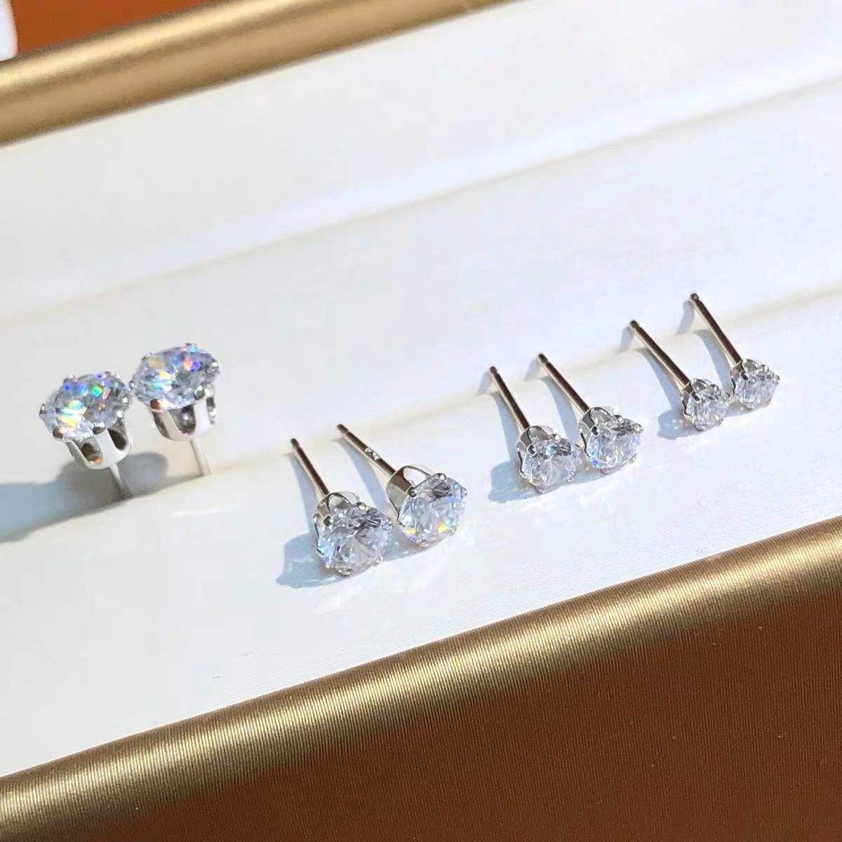 Fine jewelry moissanite earrings featuring brilliant round stones set in classic six-prong solid 18K gold settings.
