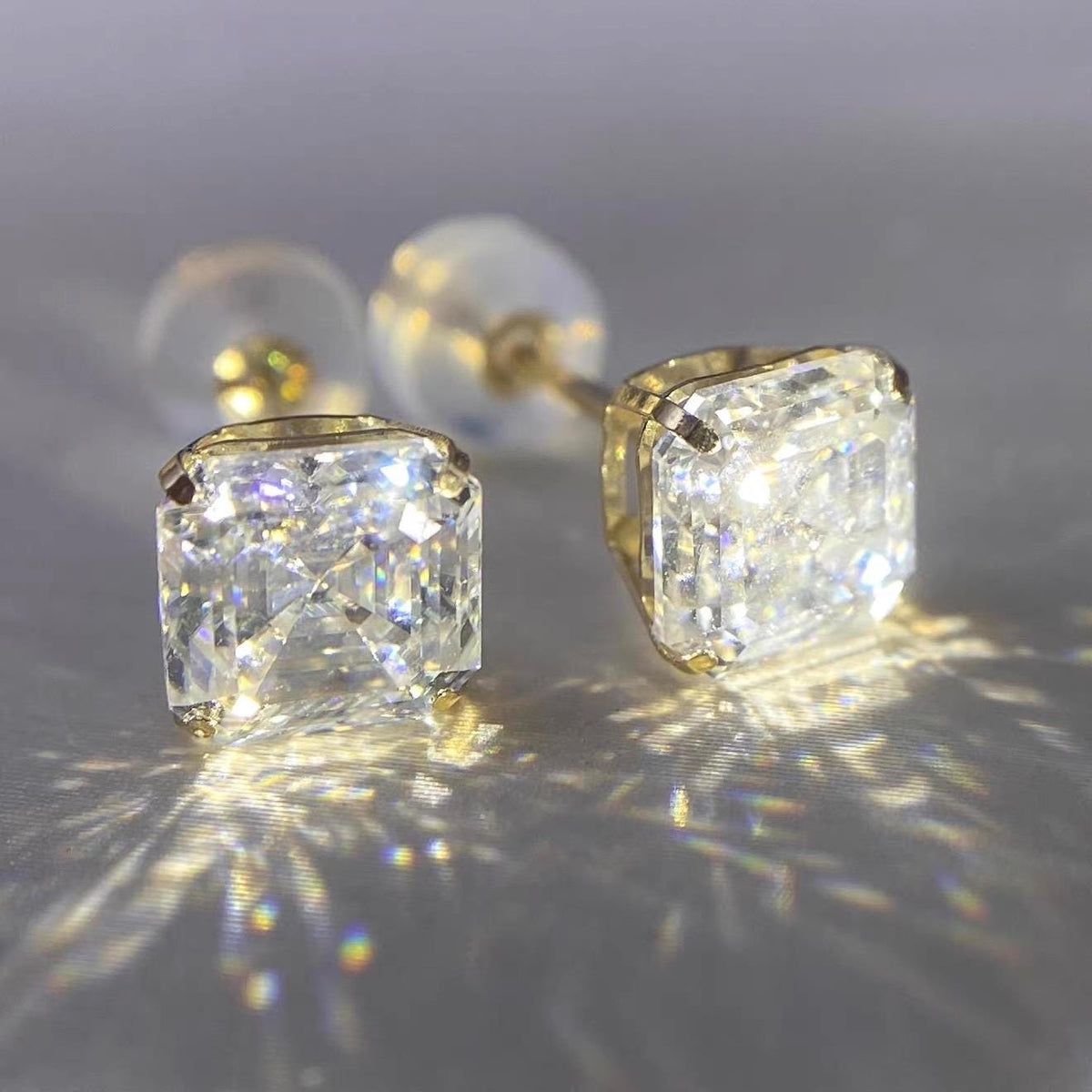 Macro view of 4-prong Asscher cut moissanite stud earrings showing detailed solid gold craftsmanship.
