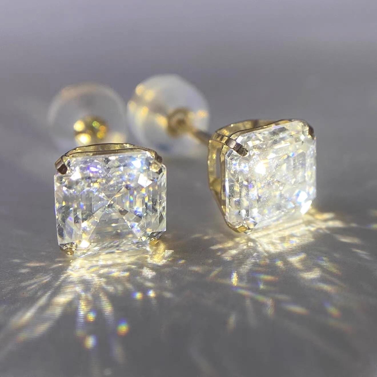 Macro view of 4-prong Asscher cut moissanite stud earrings showing detailed solid gold craftsmanship.