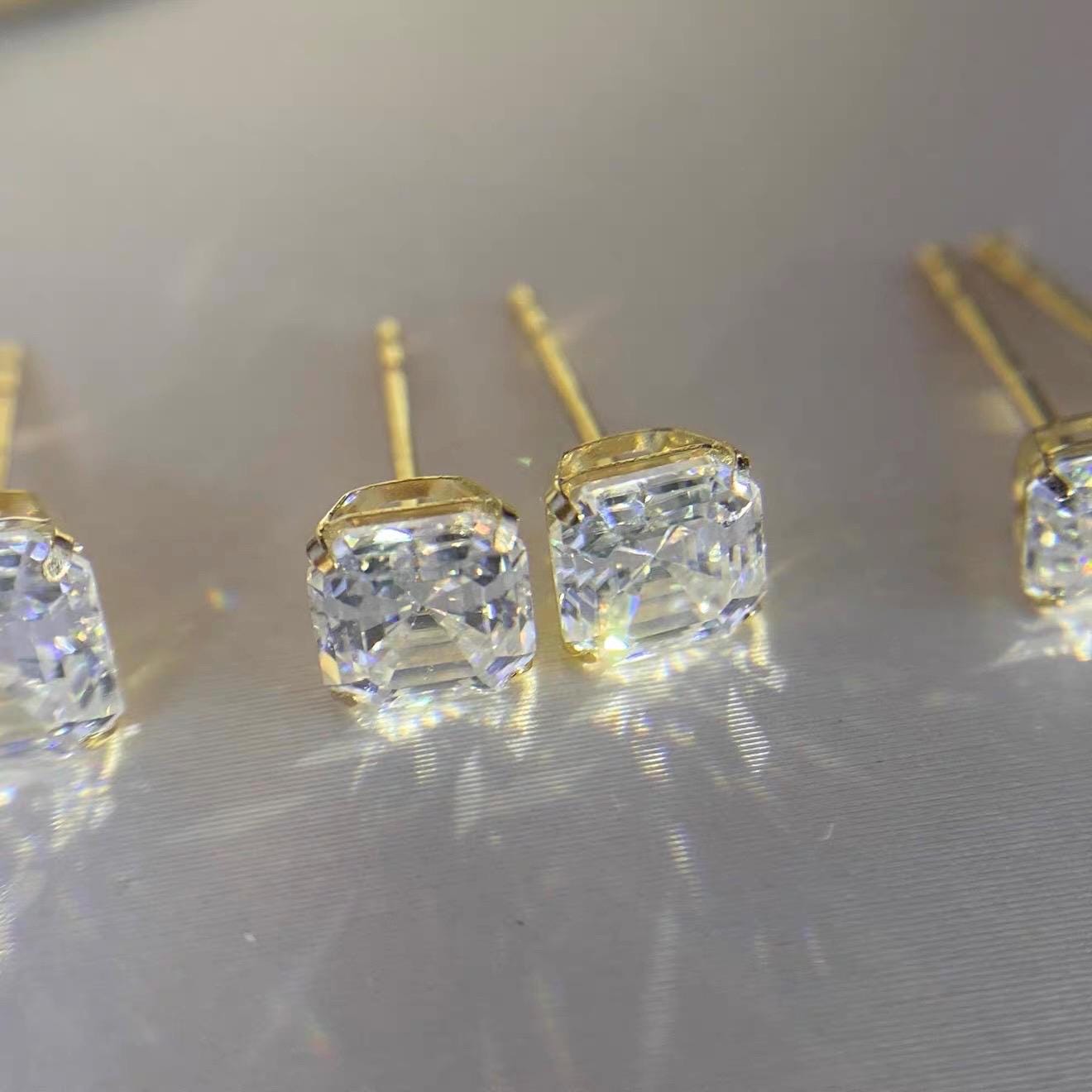 Brilliant clear moissanite stud earrings with elegant square cuts and minimalist 4-prong gold settings.