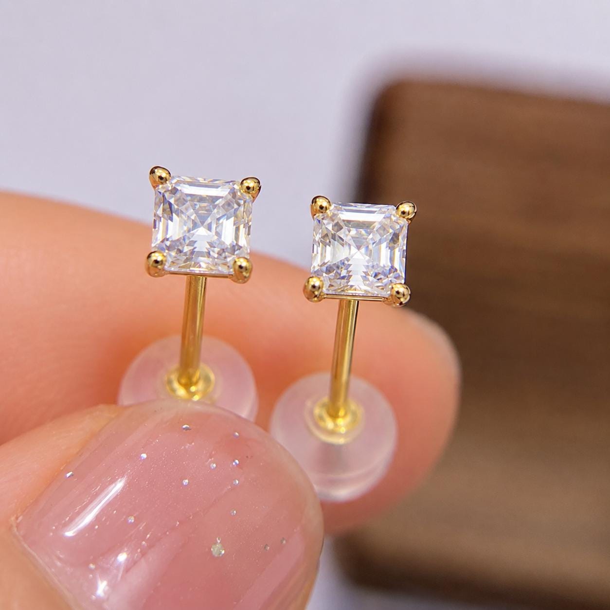 Side view of Asscher cut moissanite earrings showing solid 14K gold posts and secure basket settings.
