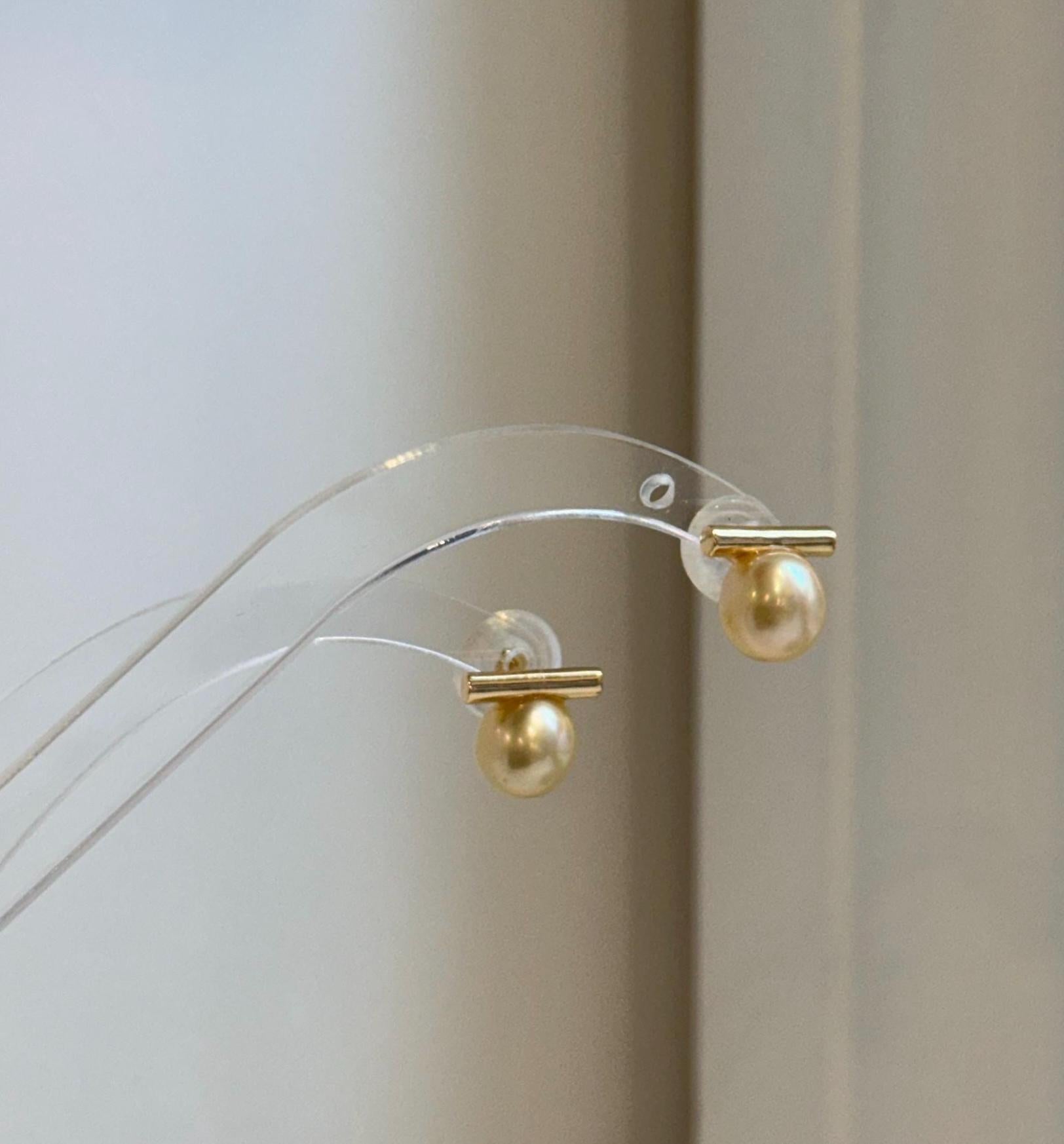 High-luster golden saltwater pearl drop earrings in a contemporary minimalist design.
