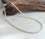 Elegant white small pearl strand showcasing bright mirror-like luster and solid 18K gold details.