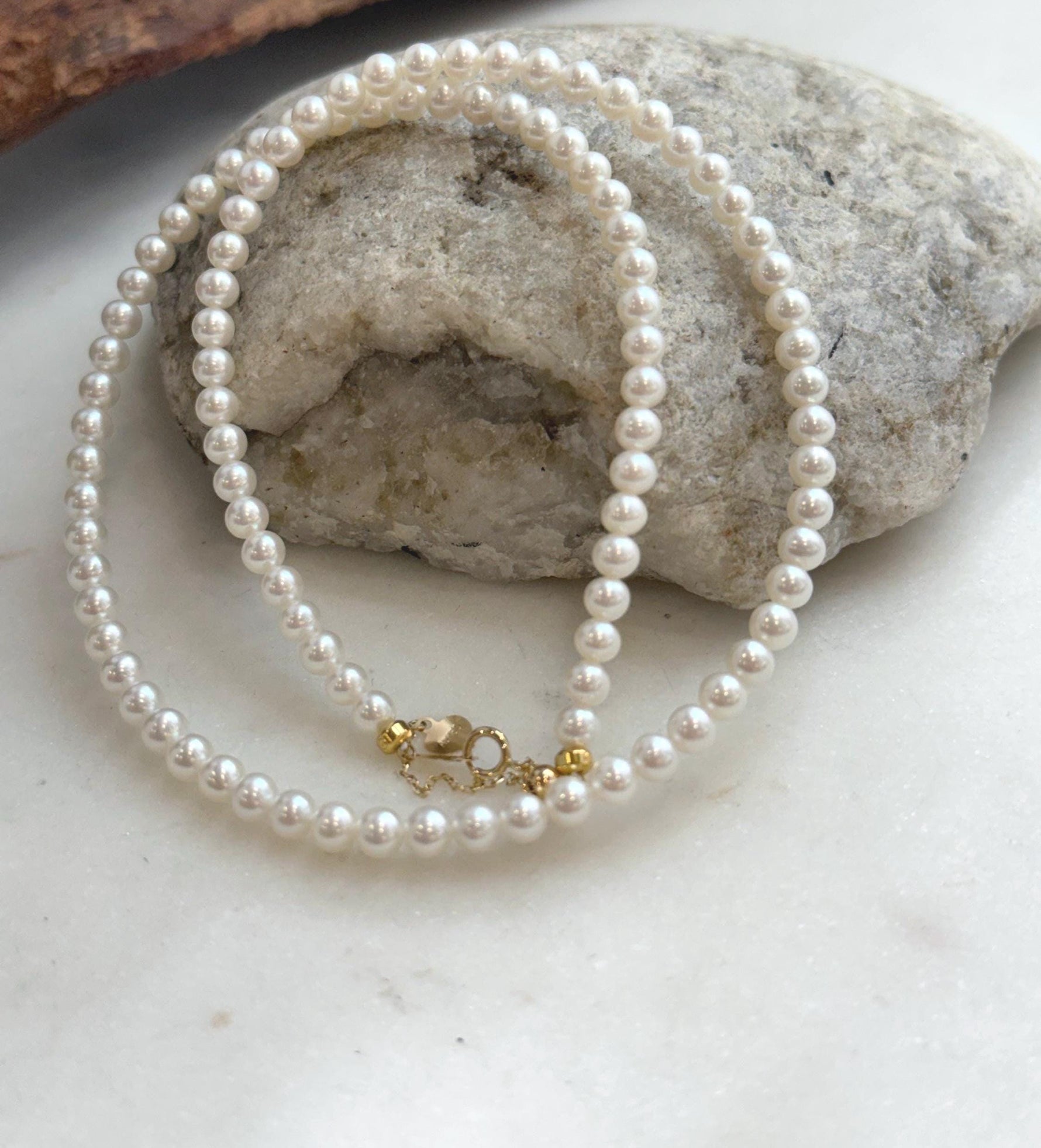 Classic small white pearl necklace strand with intense luster and solid 18K gold closure.