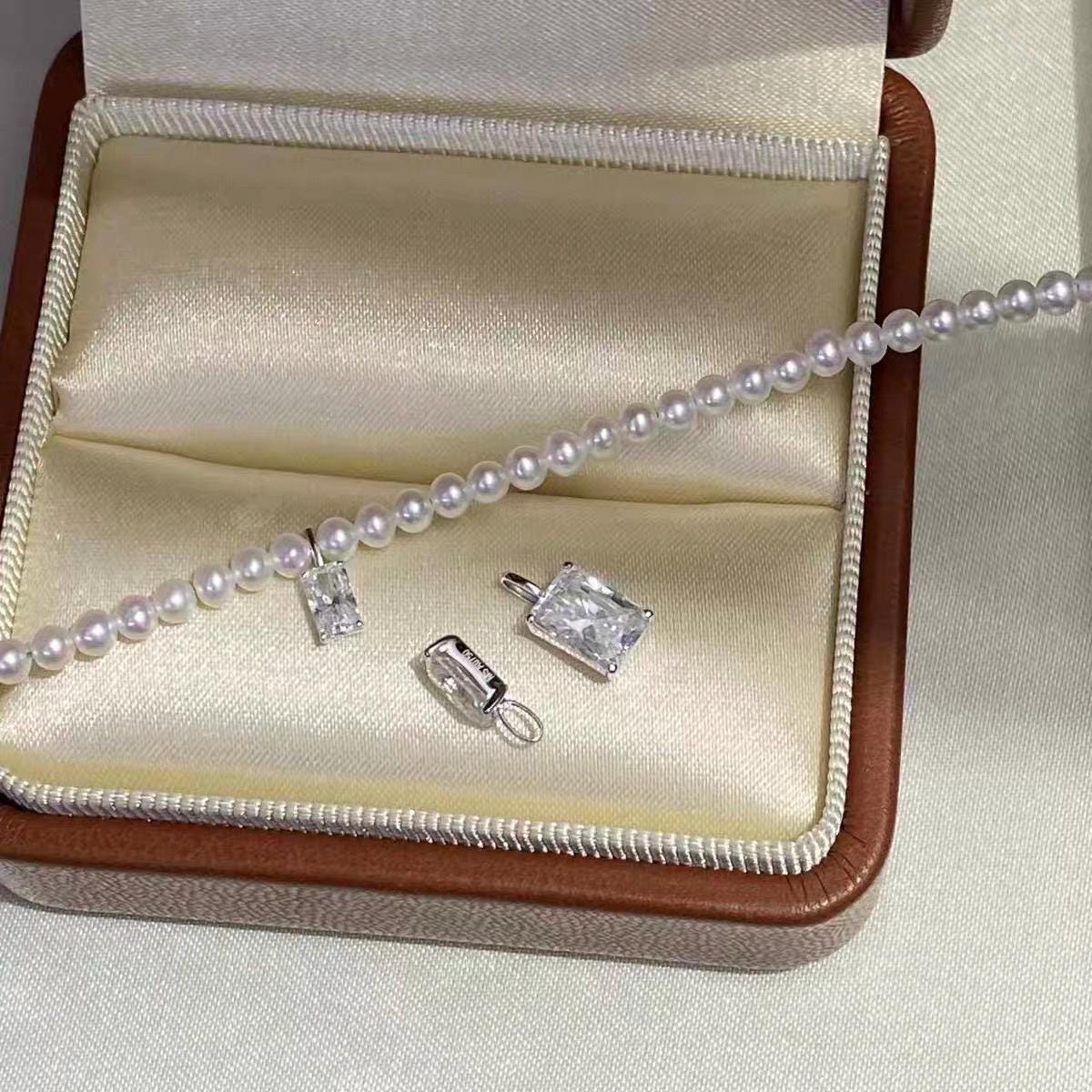 Dainty clear moissanite charm with a classic rectangular emerald cut for pearl bracelets and necklaces.
