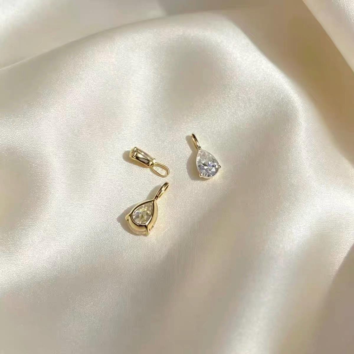Dainty pear cut moissanite pendant charm available in yellow gold and white gold styles.
