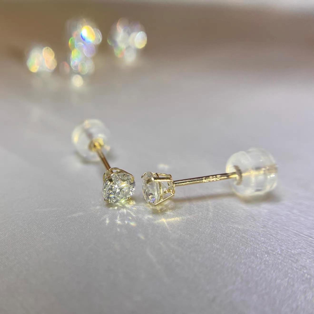 Close-up of round brilliant moissanite gemstones secured in elegant 4-prong 14K gold settings.
