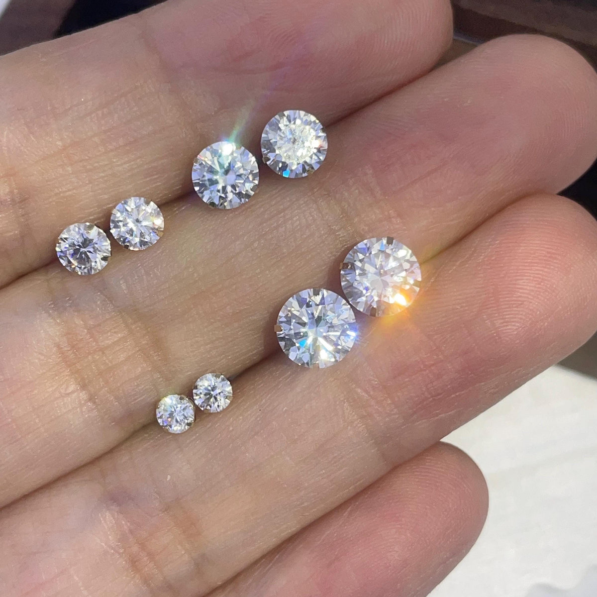 Minimalist round moissanite earrings with solid 14K gold posts and classic four-prong settings.
