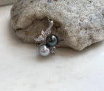 Close-up of two genuine Tahitian pearls showing smooth surfaces, deep natural tones and reflective mirror luster.