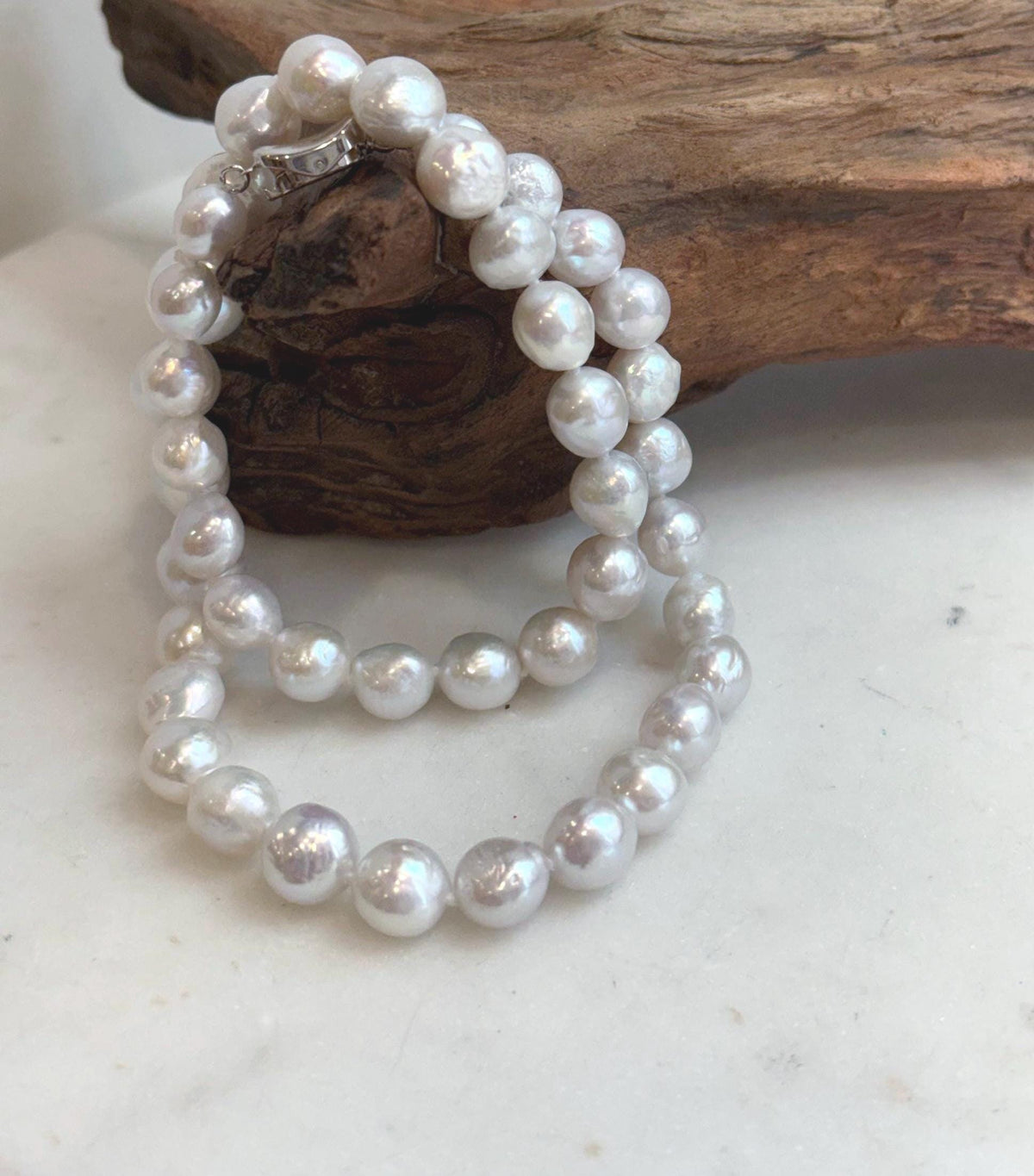 White freshwater pearl necklace showing strong iridescent pink and rainbow overtones under natural light.