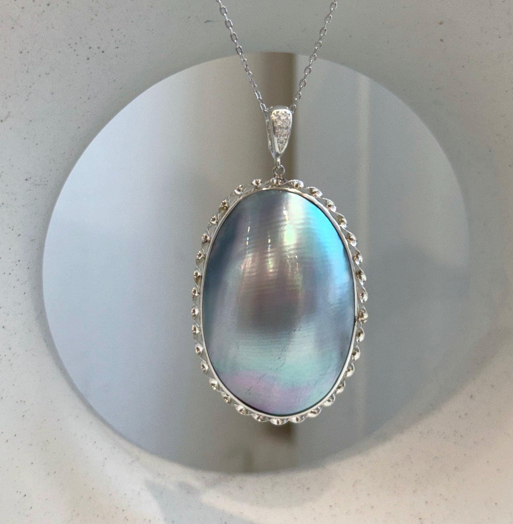 Large ocean Mabe pearl pendant with luminous blue iridescent tones