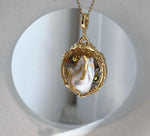 Vintage style white baroque pearl brooch with iridescent overtones and decorative gold foiled details.