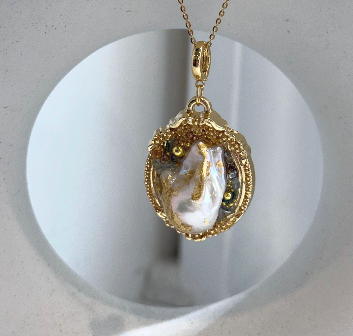White iridescent baroque pearl pendant brooch with strong natural luster and vintage gold tone setting.