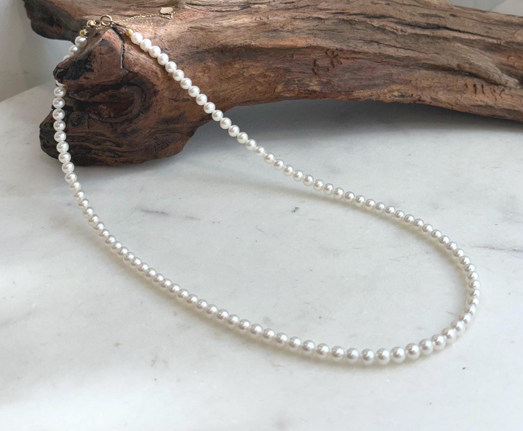 Elly’s white small pearl necklace strand with extreme mirror luster and solid 18K Au750 gold clasp.