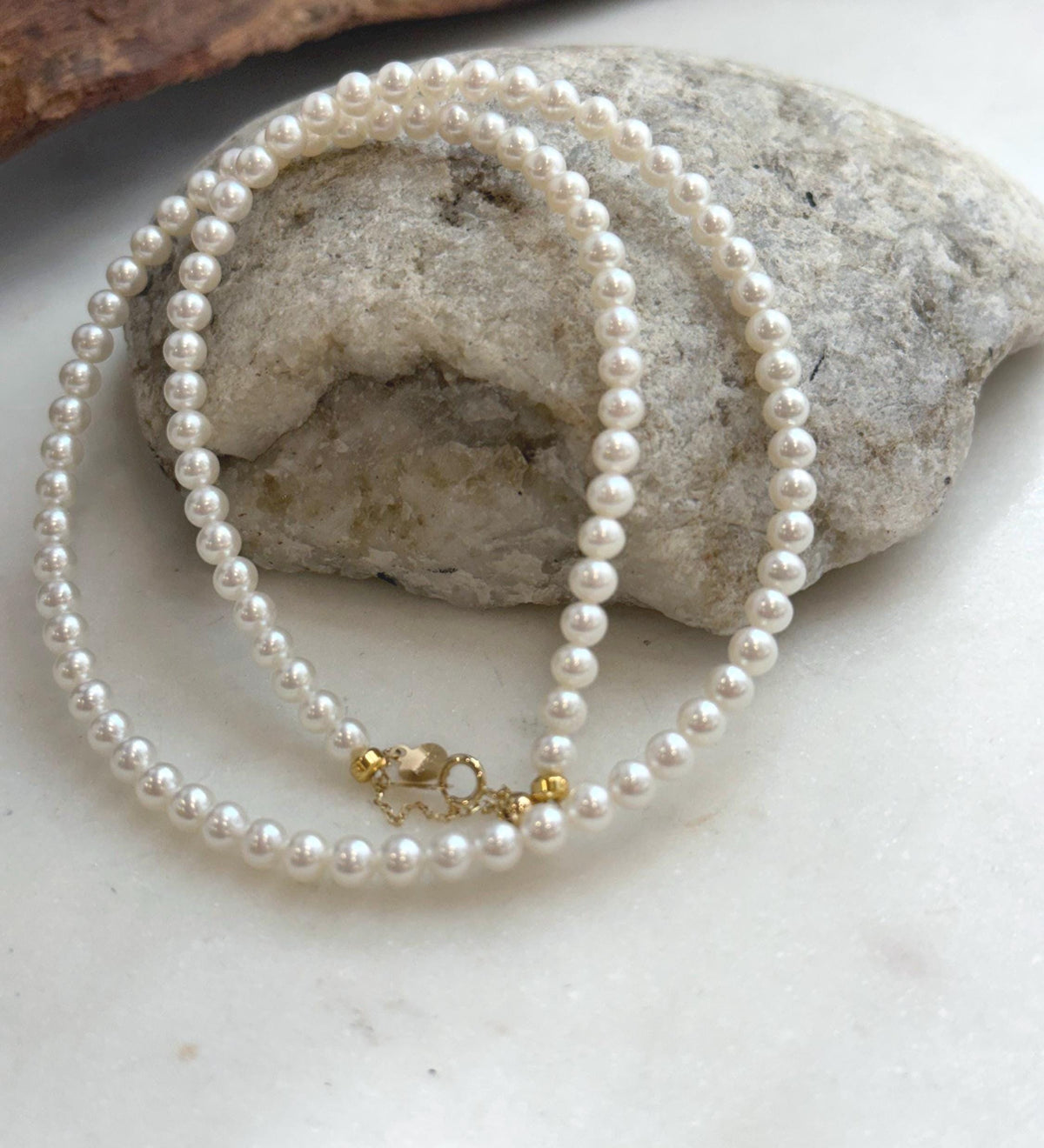 Fine white pearl necklace strand with exceptional reflective luster and classic 18K Au750 gold closure.