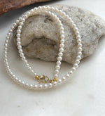Fine white pearl necklace strand with exceptional reflective luster and classic 18K Au750 gold closure.