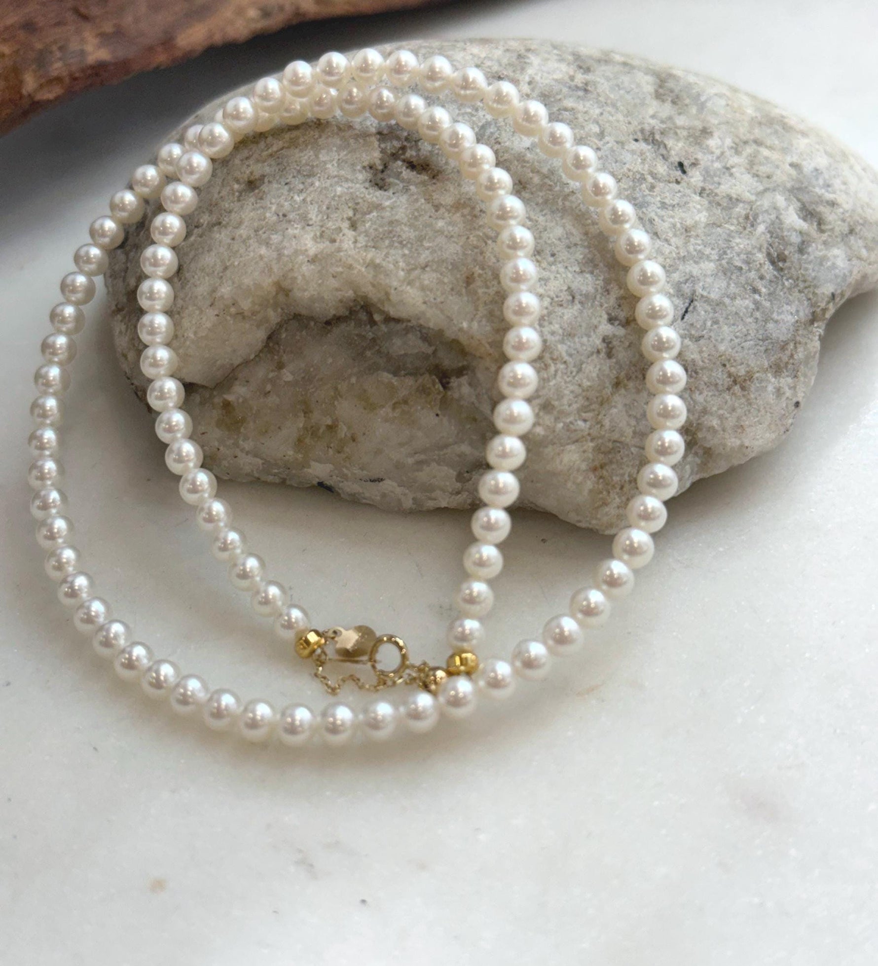 Fine white pearl necklace strand with exceptional reflective luster and classic 18K Au750 gold closure.