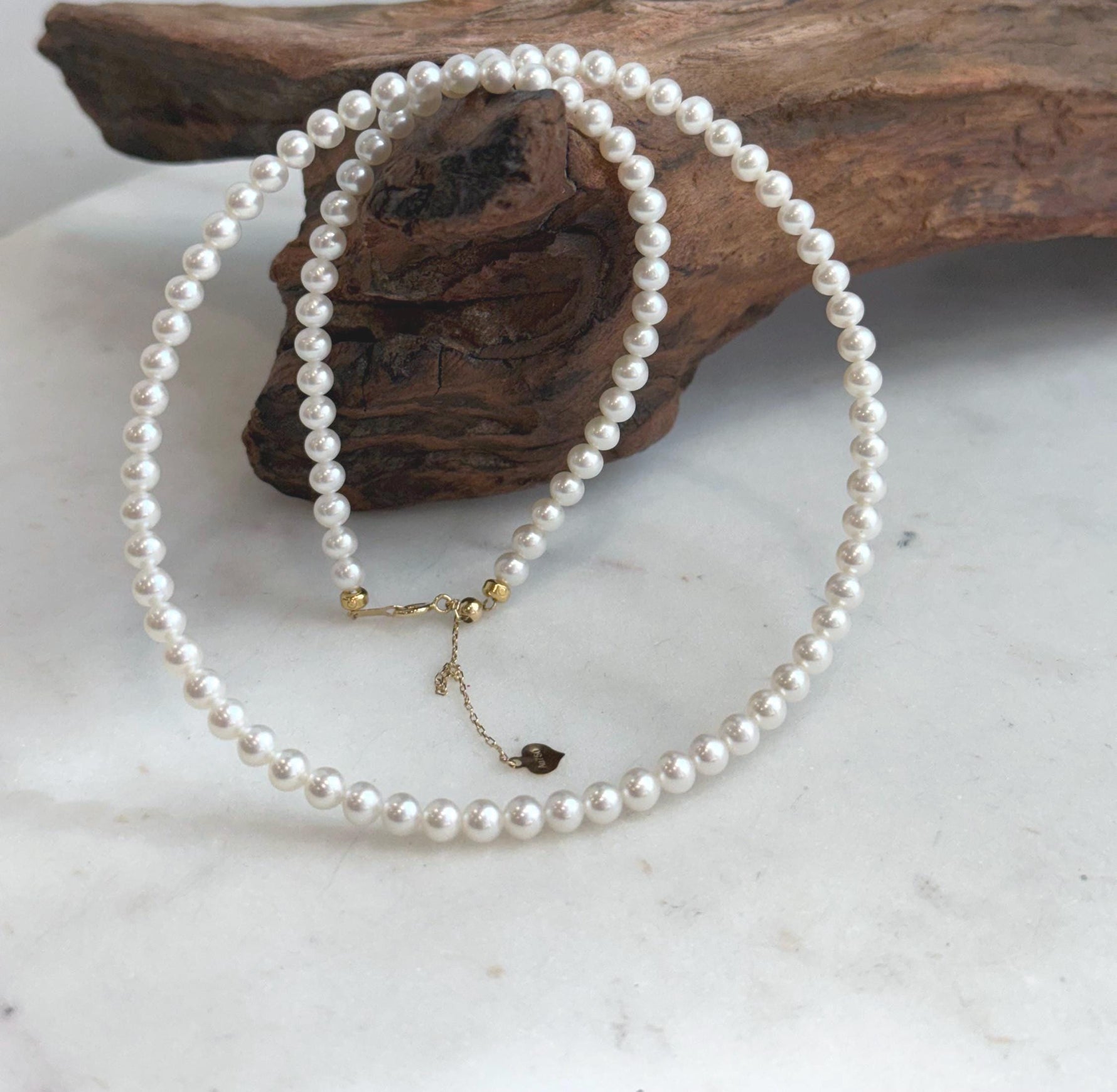 Timeless white small pearl strand with radiant mirror luster and refined solid 18K Au750 gold clasp.