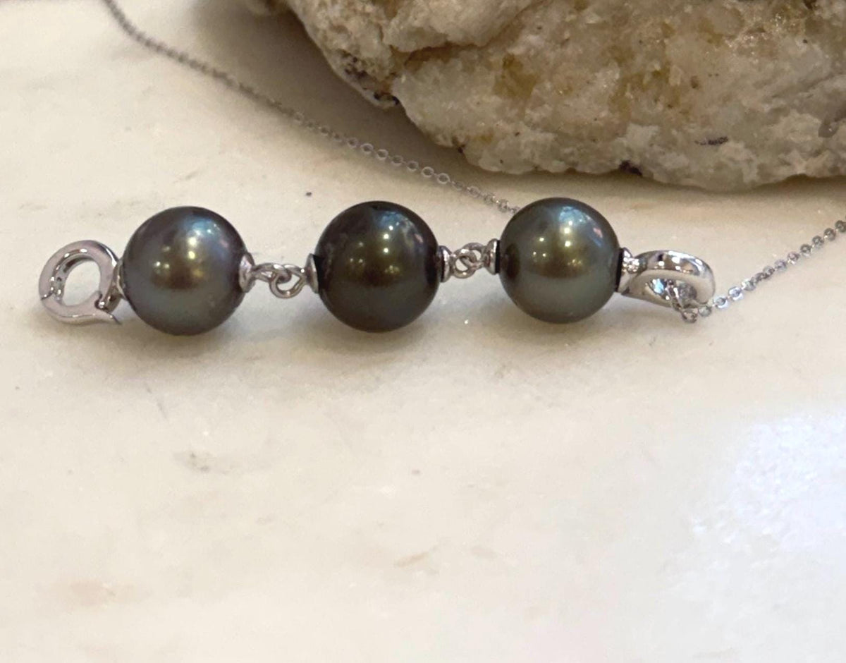 Platinum and hunter Tahitian pearls with mirror-like metallic luster on a silver necklace extender.