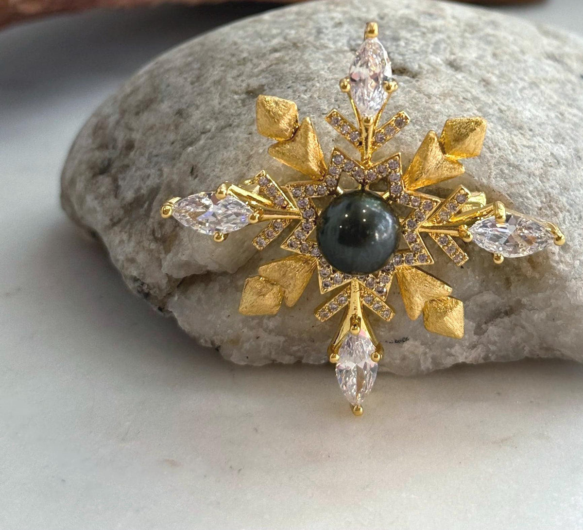 Genuine Tahitian black pearl set in a detailed snowflake brooch pendant design.