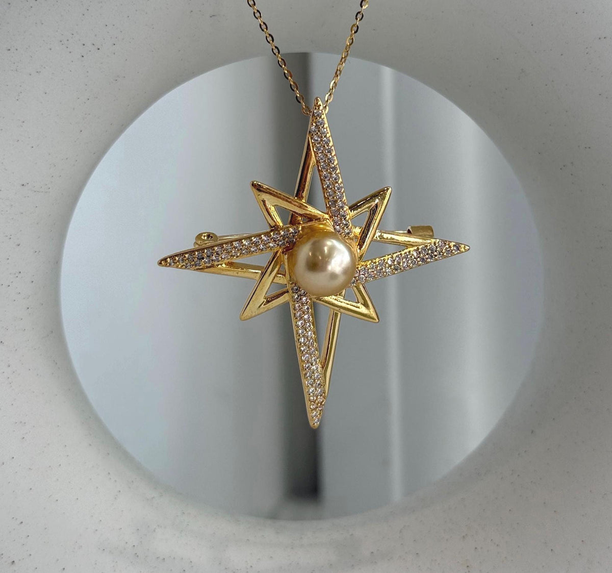 Close-up of a deep tea golden South Sea pearl set in an elegant star-shaped brooch pendant design.