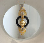 South Sea golden pearl pendant suspended from a delicate gold tone chain on a cream display.