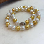 White and gold pearl necklace photographed beside a piece of natural driftwood.